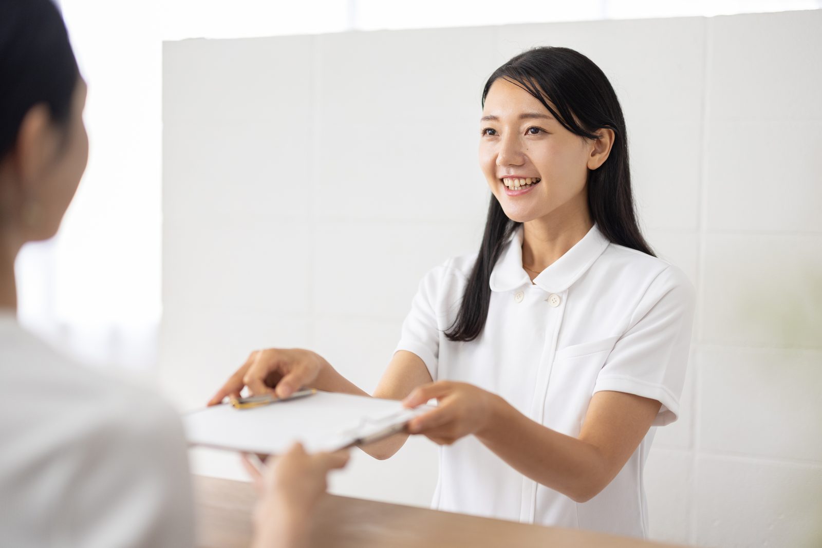 クリニックの受付で応対するスタッフ（イメージ）
